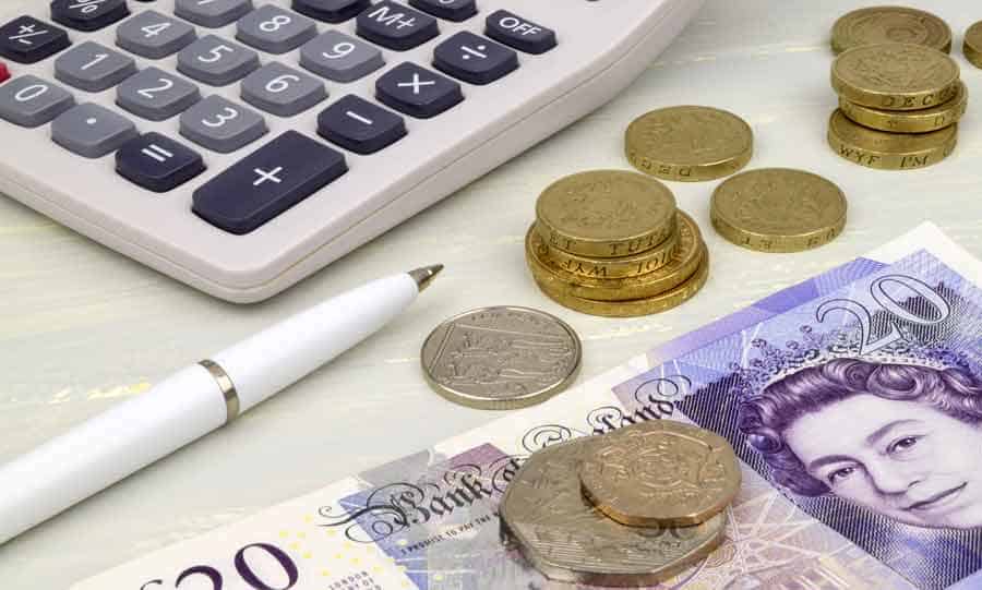 £20 bill along side several coins, pen and calculator illustrating Loan Skipper loan calculation