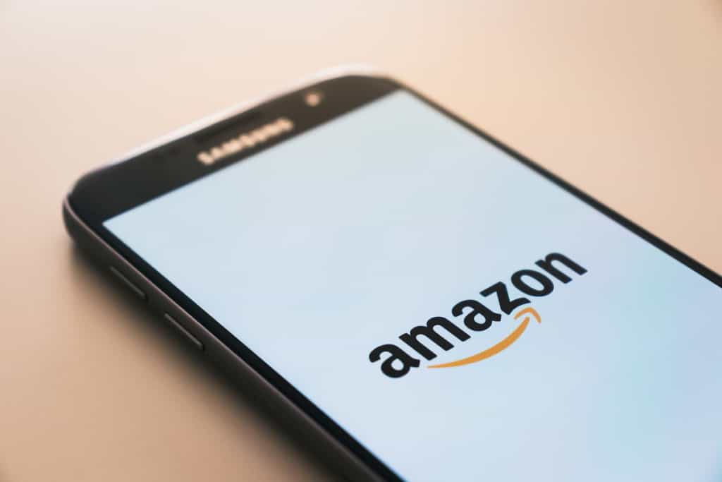 In this photo a smartphone on a table with Amazon logo on a screen.