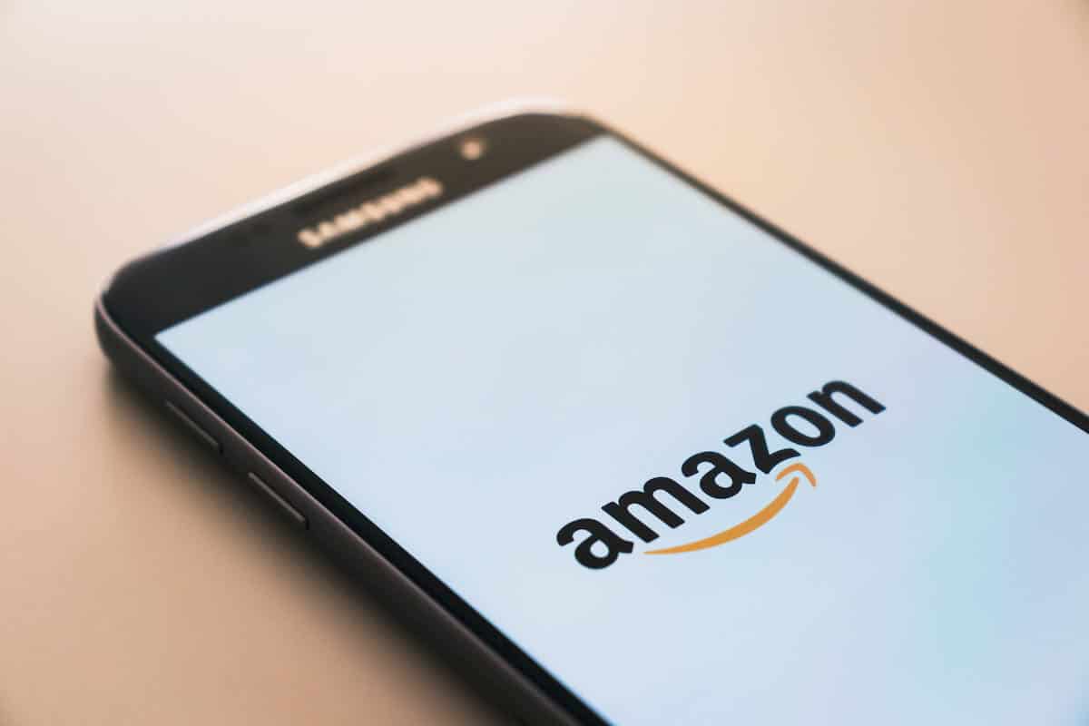 In this photo a smartphone on a table with Amazon logo on a screen.